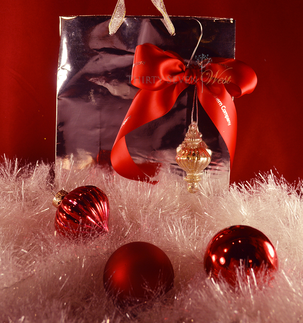 Custom printed red ribbon with silver logo or lettering paired with silver bag and ornament.  Simple statement with elegant gift bag makes any gift more impactful.